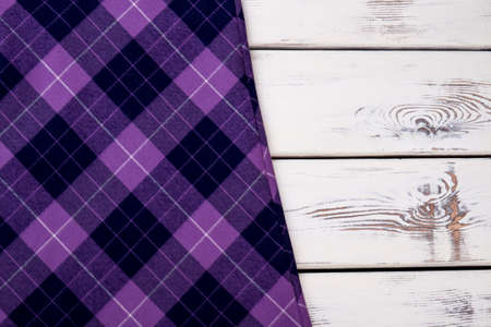 Purple violet checkered plaid clothes material. Close up macro view. White wooden desks surface background.の写真素材