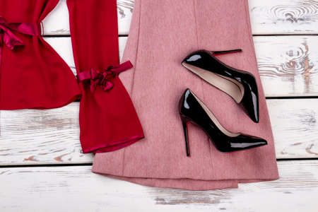 Close up black shiny high heel shoes. Flat lay, red and pink clothes.の写真素材