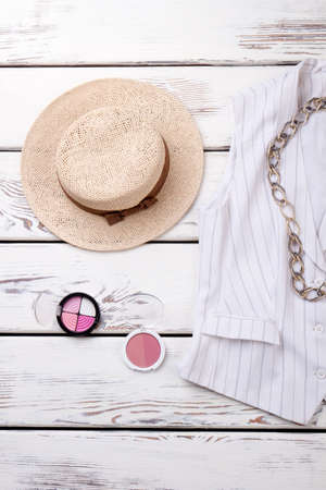 Straw summer hat and cosmetic powder. White striped jacket with chain necklace.の写真素材