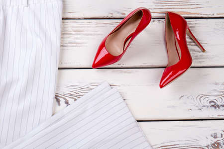 Red high heel shoes, top view. White folded striped trousers.の写真素材