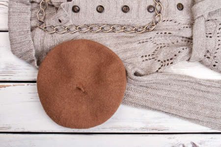 Brown berete hat on grey woolen coat. Bright wooden desk background.の写真素材