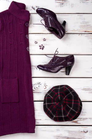 Purple woolen coat, hat and pair of shoes. Bright wooden desk background.の写真素材
