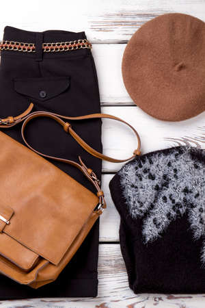Set of warm female clothing. Vertical cropped view black trousers with chain belt, sweater, purse and hat.の写真素材