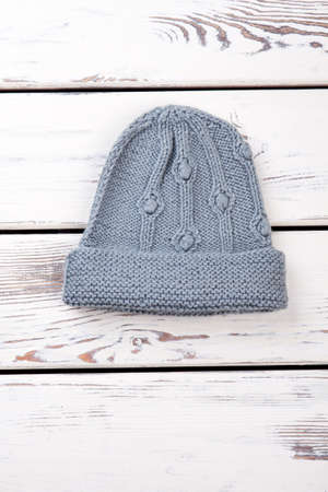 Winter womens woolen hat. Vertical cropped view, white wooden background.