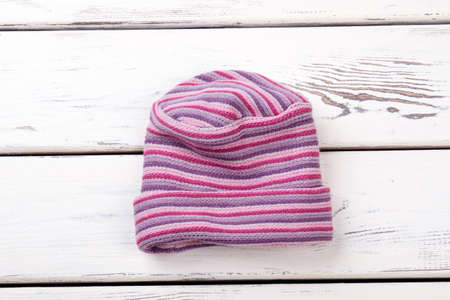 Pink striped woolen hat. Flat lay, top view. White wooden desks surface background.の写真素材