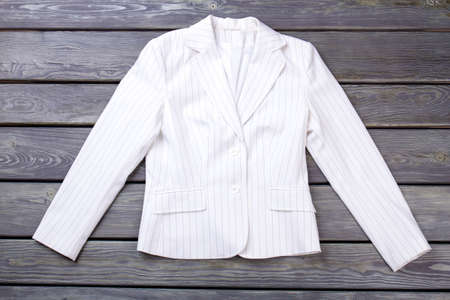 Flat lay white jacket on dark surface background. Striped vest, top view against wooden background.の写真素材