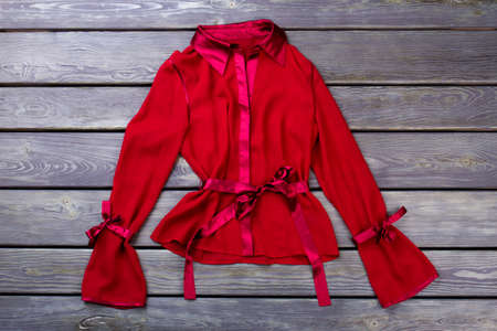 Stylish polyester red jacket. Flat lay, grey wooden surface background.の写真素材