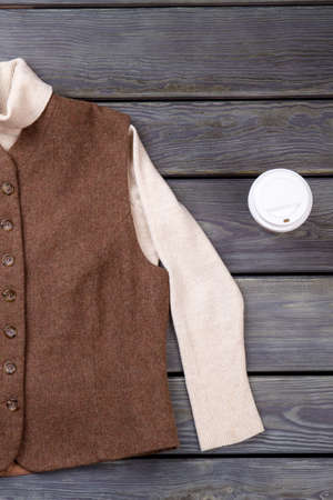Vintage brown jacket and cup of coffee, flat lay. Grey wooden surface background.の写真素材