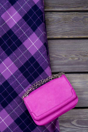 Top view purple handbag and checkered skirt. Grey wooden surface background.の写真素材