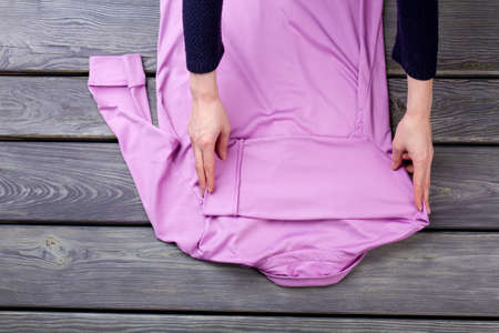 Pink blouse folding, back view. Grey wooden surface background.の写真素材