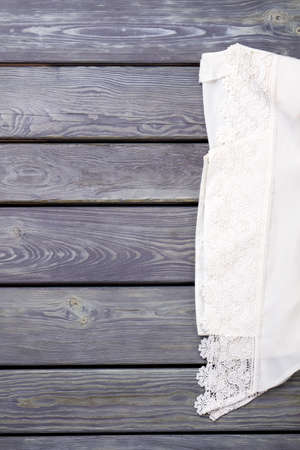 White lace clothing, top view. Flat lay. Grey wooden desk surface background.の写真素材