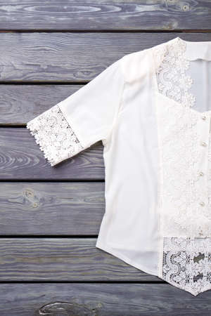 Flat lay white lace shirt. Fancy stylish blouse. Grey wooden background.の写真素材