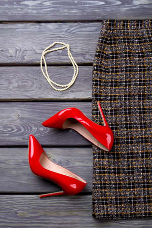 Woman shoes and beads necklace. Grey wooden desk surface background.の写真素材