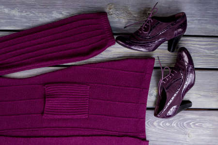 Purple wool cloth and pair of shoes. Wooden desk surface background.の写真素材