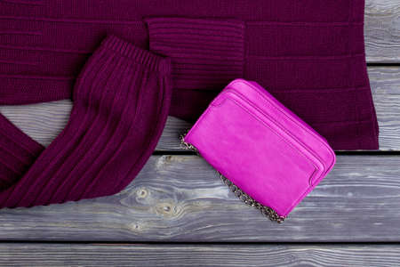 Pink leather handbag and wool sweater. Wooden desk surface background.の写真素材
