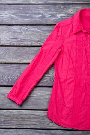 Pink shirt sleeve, flat lay. Wooden desk surface background.の写真素材