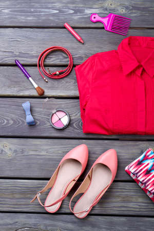 Various makeup products, shirt and shoes. Wooden desk surface background.の写真素材