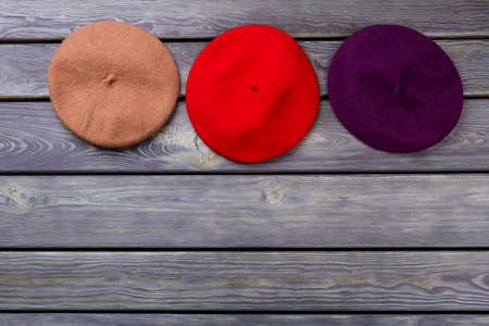 Row of colourful berete hats. Wooden desk surface background.の写真素材