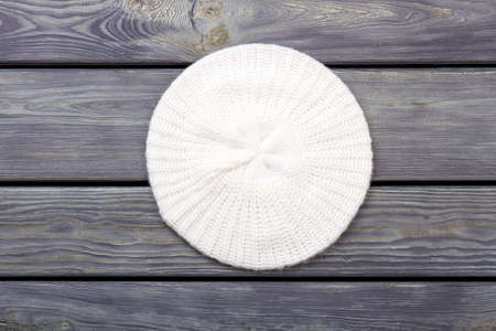 White wool knitted hat, top view. Flat lay, wooden desk surface background.の写真素材