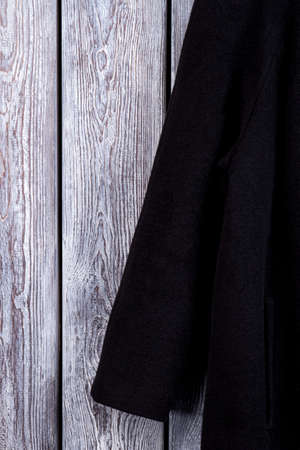 Close up black coat sleeve. Wooden desk background.の写真素材