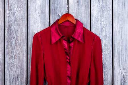Red silk collar. Clothes on hanger. Top view, wooden background.の写真素材