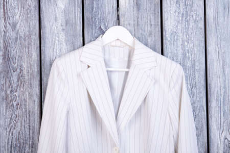 Close up white business jacket on hanger. Dark wooden background. Top view.の写真素材