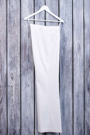 White business trousers on hanger. Dark wooden background.の写真素材