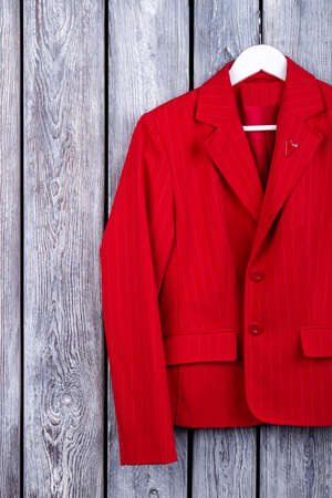 Stylish red business suit for women. Fancy jacket. Top view, wooden surface background.の写真素材
