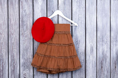 Flat lay brown skirt and red hat on the table. Grey desk surface background.の写真素材