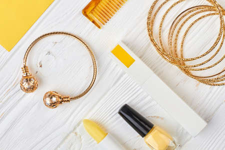 Set of female cosmetics and accessories. Ladies gold jewelry and makeup products on white wooden background, top view.の写真素材