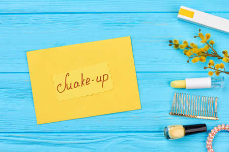 Beautiful cosmetics set, top view. Flat lay decorative cosmetics, accessories, pussy willow catkin. Yellow card on blue wooden background. Beauty and spring. Natural cosmetics concept.の写真素材