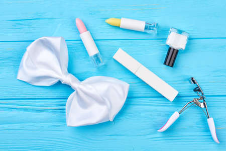 Cosmetics and accessories, wooden background. White bow tie and accessories for natural makeup, blue wooden background. Young girl beauty makeup essentials.の写真素材