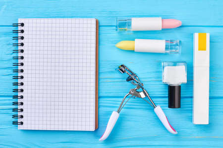 Cosmetics and paper notebook. Flat lay of decorative cosmetics, eyelashes curler and blank paper notepad.の写真素材