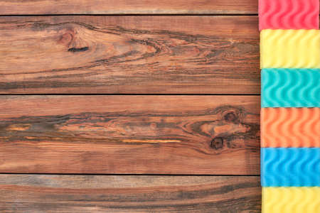 Row of kitchen sponges, copy space. Set of multicolored sponges for dish washing on brown wooden background, space for text.の写真素材