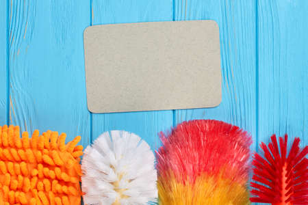 Spring cleaning equipment on colorful background. Set of multicolored brushes for house cleaning and empty paper card. Housekeeping and cleaning concept.の写真素材