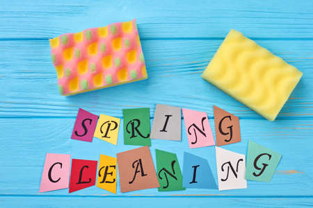 Colorful paper cut letters spring cleaning. Kitchen sponges and text spring cleaning. Spring cleaning blue wooden background.の写真素材