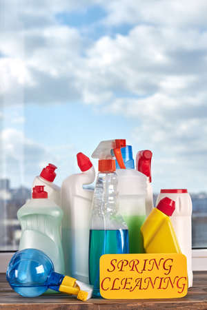 Variety of bottles with cleaning liquid. House cleaning products on window sky background. Make your...
