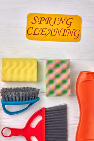 Spring cleaning concept with supplies. Kitchen sponges, brushes and cleaning liquid on white wooden background. Cleaning service concept.の写真素材