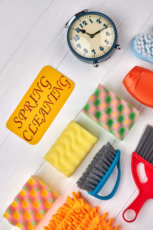House cleaning supplies, top view. Set of sponges and brushes for spring cleaning. Mechanical alarm clock and paper card. Get ready for spring cleaning.の写真素材