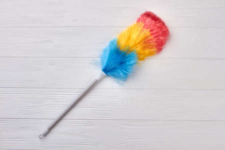 Striped fluffy duster on wooden background. Soft broom for cleaning on wooden background, copy space. Easy cleaning with colorful duster.の写真素材