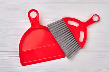 Brush and dustpan on wooden background. Set of red scoop and brush. Ready for spring cleaning.