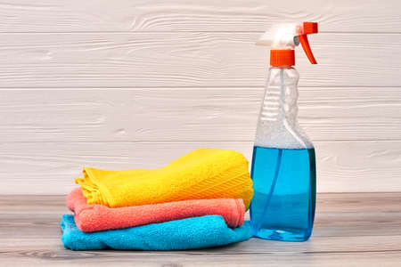 Cleaning spray bottle with plastic dispenser. Window cleaner and colorful rags o wooden background. Cleaning hacks and tips.の写真素材