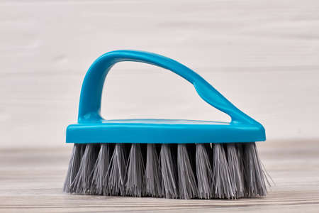 Blue clothes brush with a handle. Close up blue plastic brush on wooden background. House cleaning product.の写真素材
