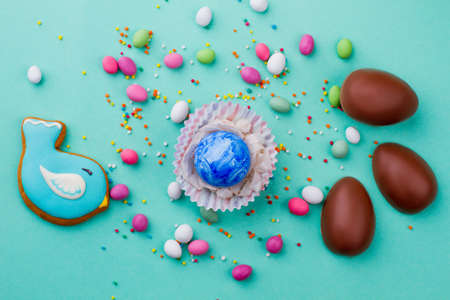 Easter egg and sweets on colorful background. Easter painted egg in paper wrapper and colorful...