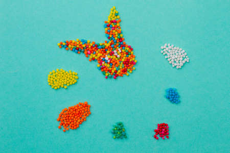 Rabbit made from colorful sweets. Sprinkle dots forming rabbit and Easter eggs, blue background. Figures made from sweets, copy space.の写真素材