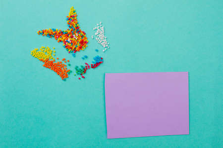 Rabbit made from sprinkle dots. Beautiful composition from colorful sweets on turquoise background. Blank card for text.の写真素材