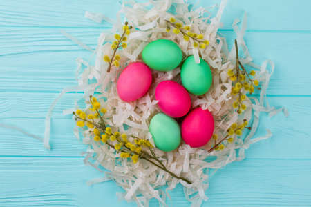 Painted Easter eggs in nest. Colorful Easter eggs, pussy willow twigs and pile of paper streamers. Easter decoration ideas.の写真素材