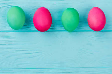 Row of colorful Easter eggs. Row of green and red Easter eggs on blue background with copy space. Idea for Easter greeting.の写真素材