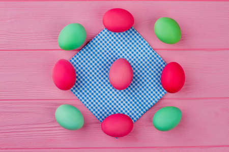 Frame from Easter eggs on pink background. Flat lay colorful Easter egs on blue vintage napkin. Easter symbol and food.の写真素材