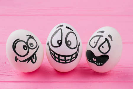 Easter eggs with funny faces. Egg with laughing face. Eggs with emotions of surprise. Close up group of eggs with drawing faces.の写真素材